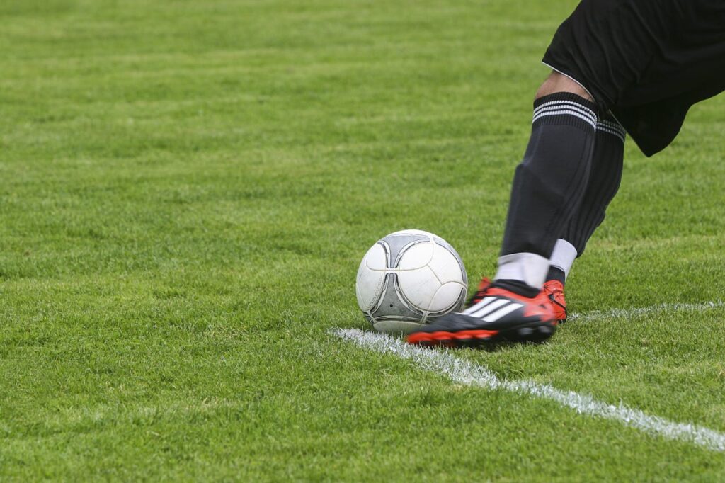 football-ball-sport-soccer-50713 Dynamic shot of a soccer player kicking the ball on a grassy field, showcasing fast-paced sports action.