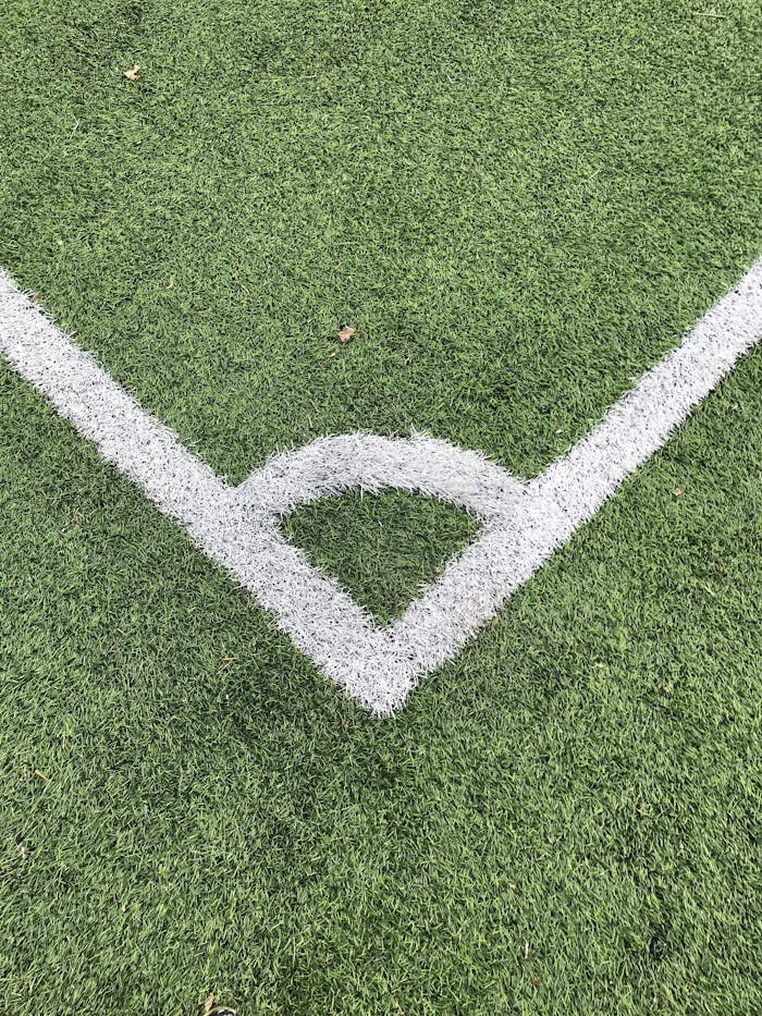 pexels-photo-3571065 Detailed close-up of a white corner line on a green soccer field turf.