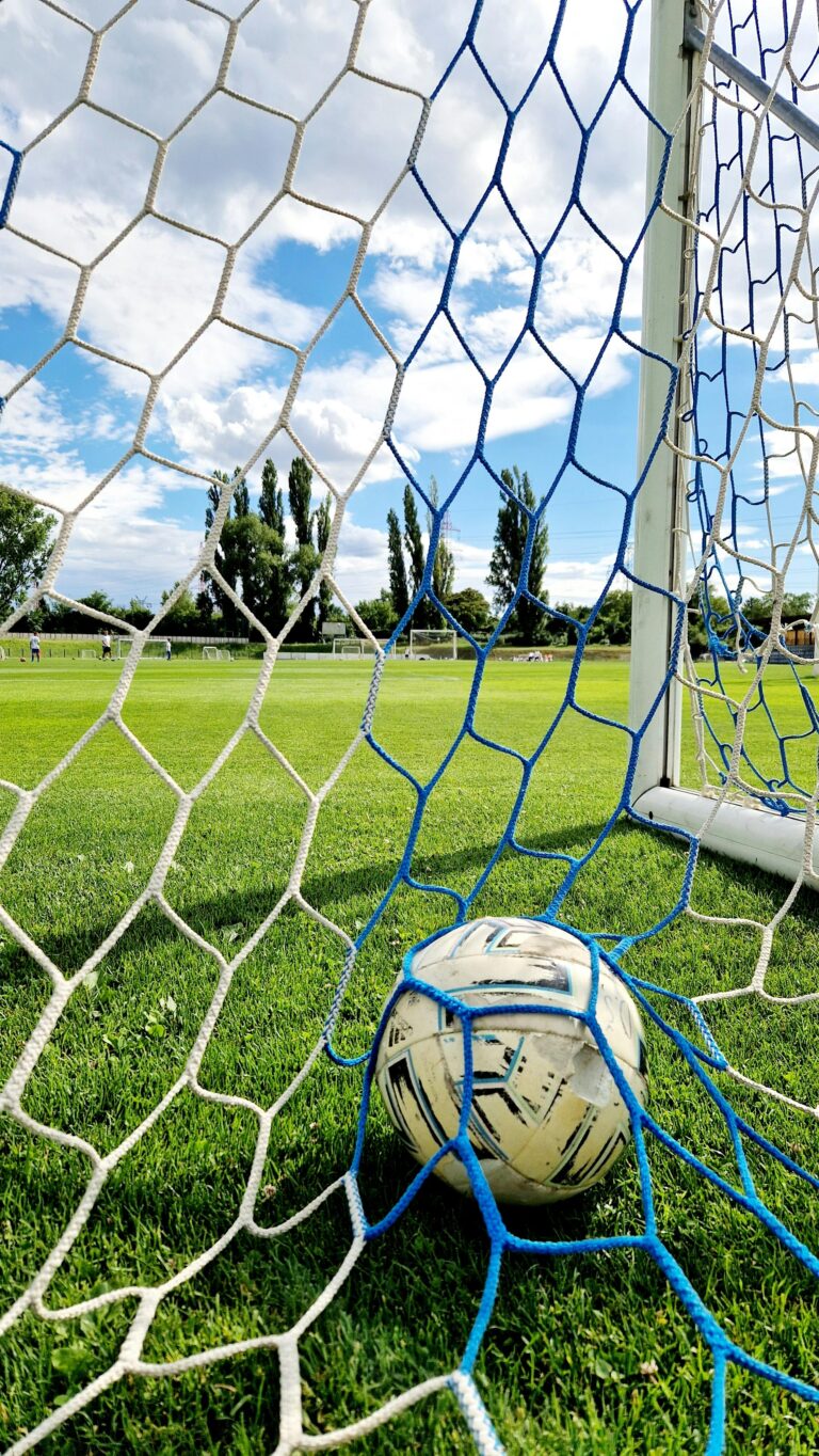 Vibrant shot of a soccer ball trapped in the goal net on a sunny day.